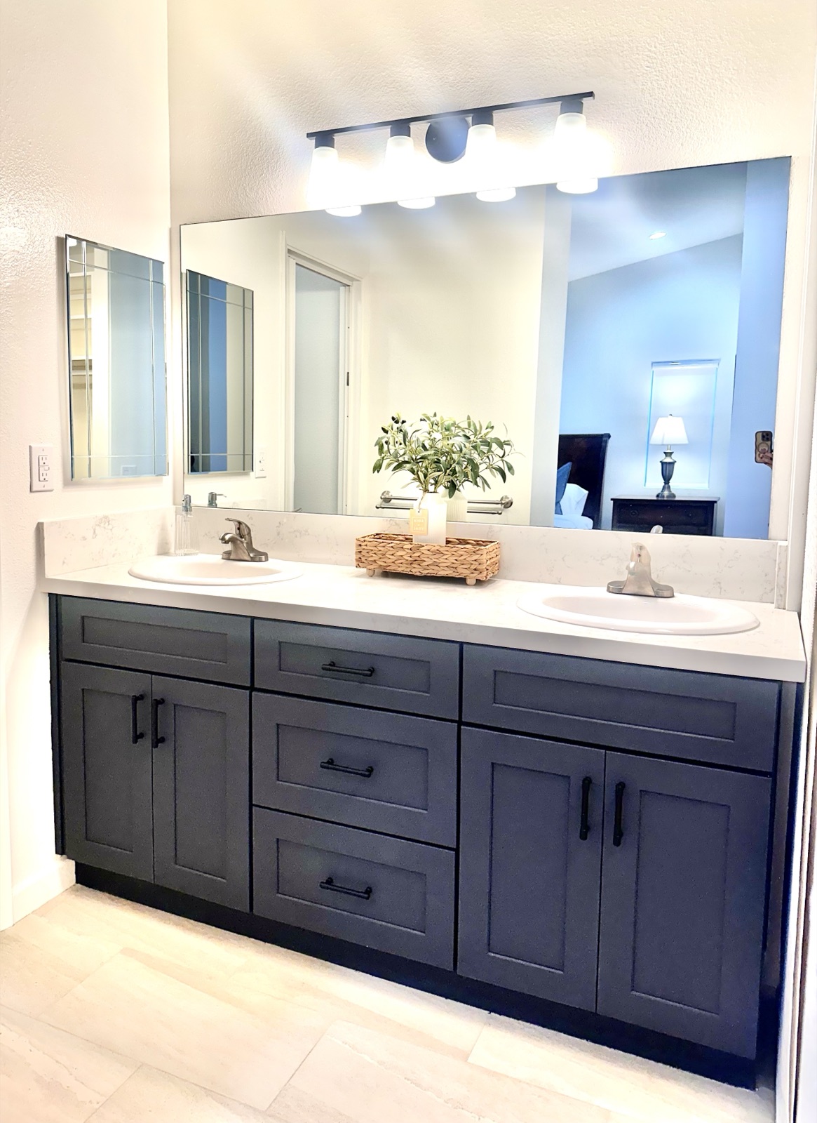 Double-vanity private bathroom with a large lit mirror and dark cabinetry