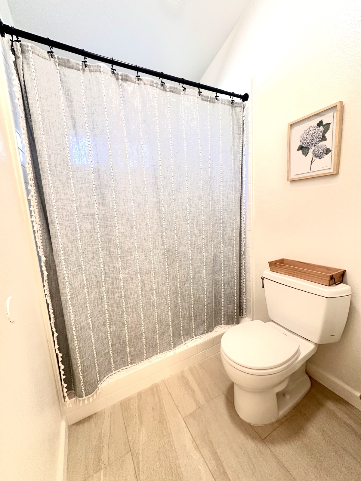 Private bathroom with a curtained shower and framed botanical art