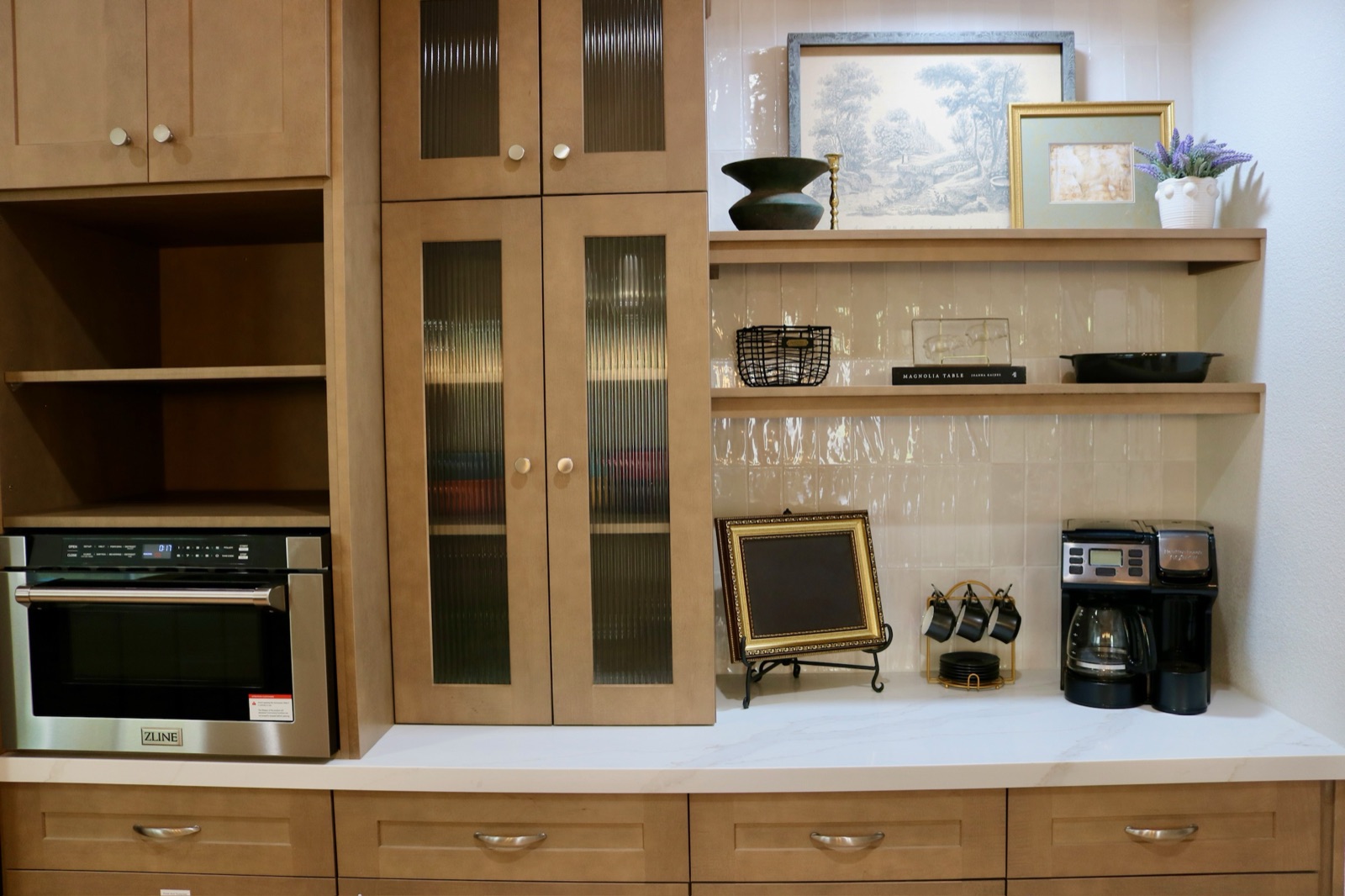 Coffee bar with built-in oven, marble counter, and framed art on open shelving