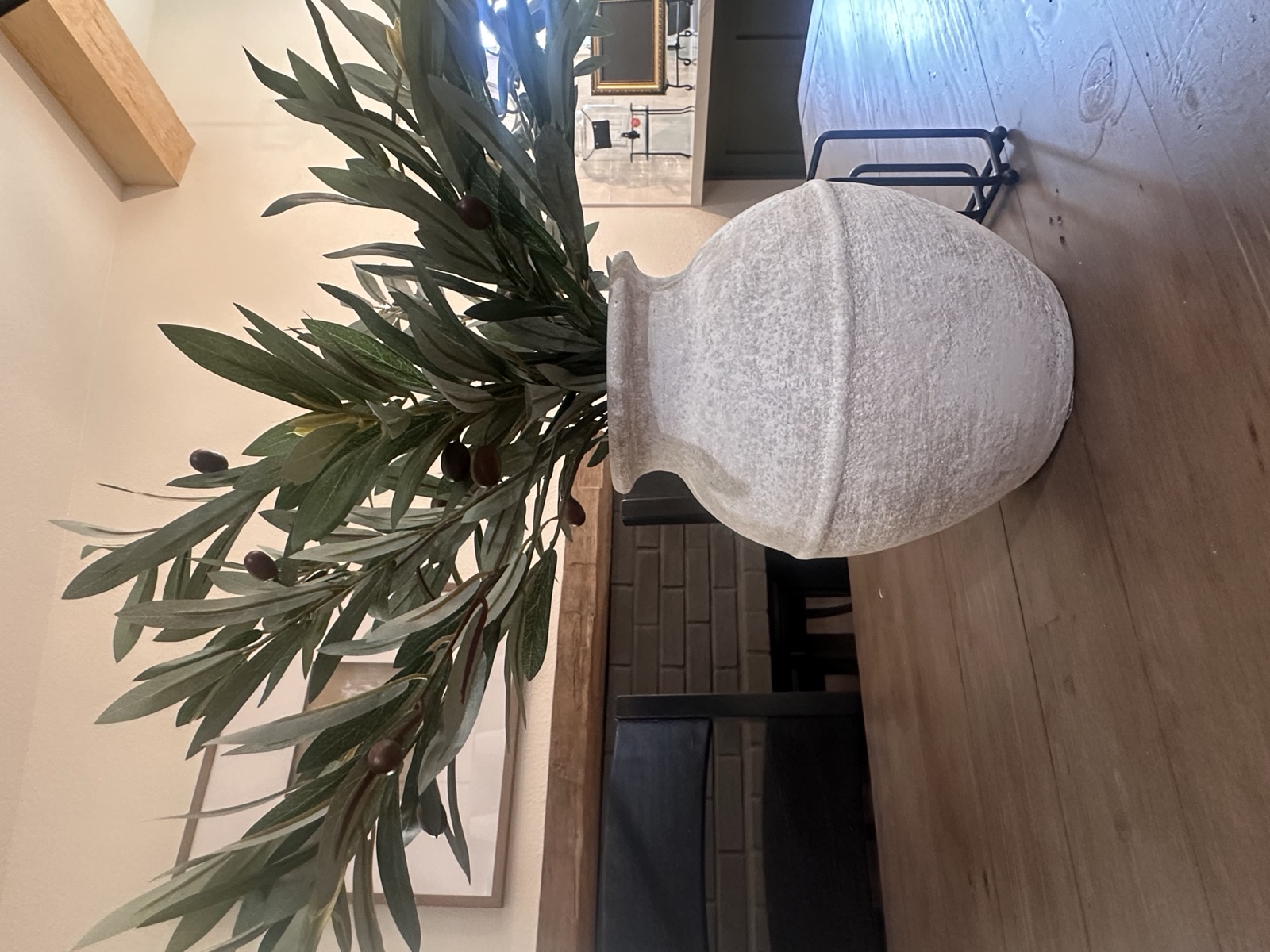Olive branches arranged in a white ceramic vase on the dining table