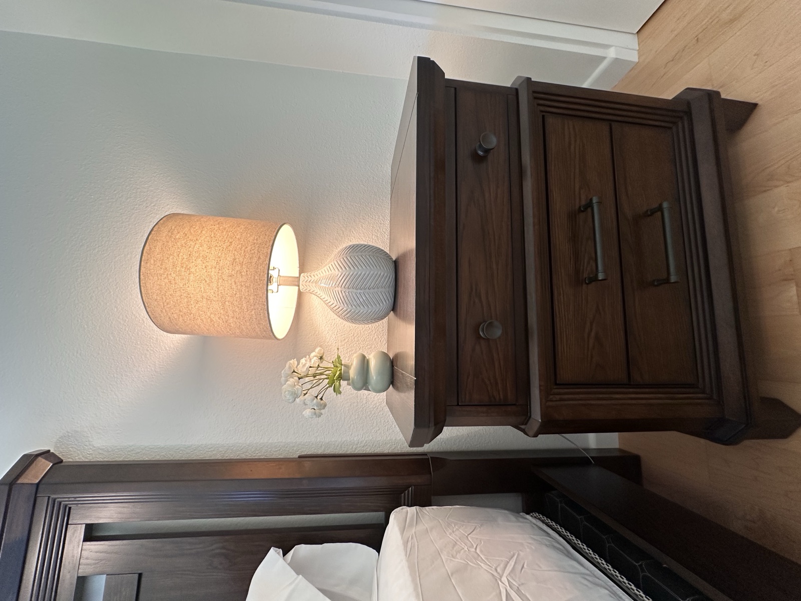 Bedside nightstand with a lit ceramic lamp and a small orchid