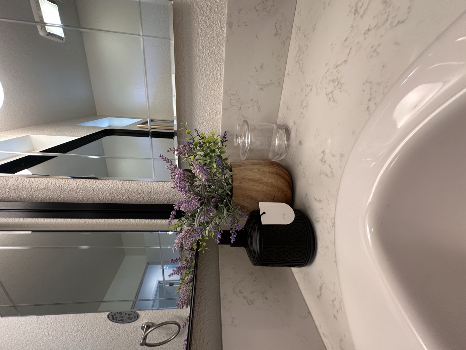 Bathroom counter detail with lavender in a wood vase on a marble top