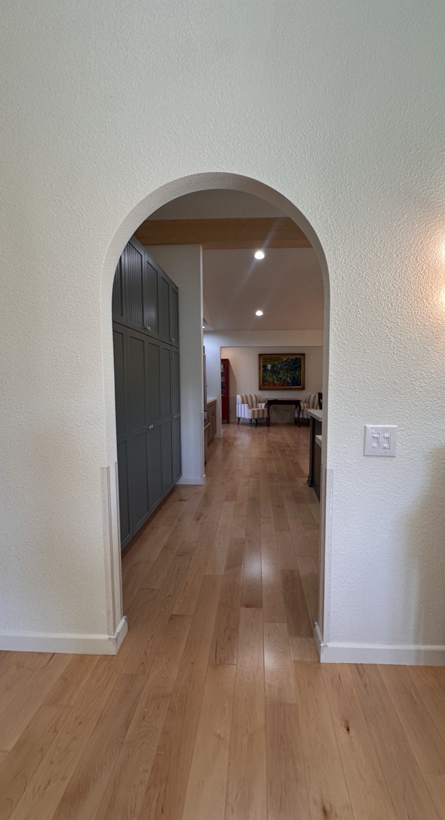 Arched interior hallway with recessed lighting leading toward the living area