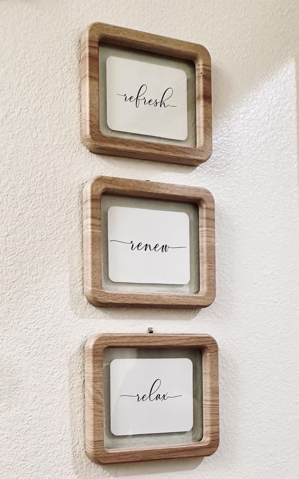 Framed word art reading refresh, renew, and relax on a bathroom wall