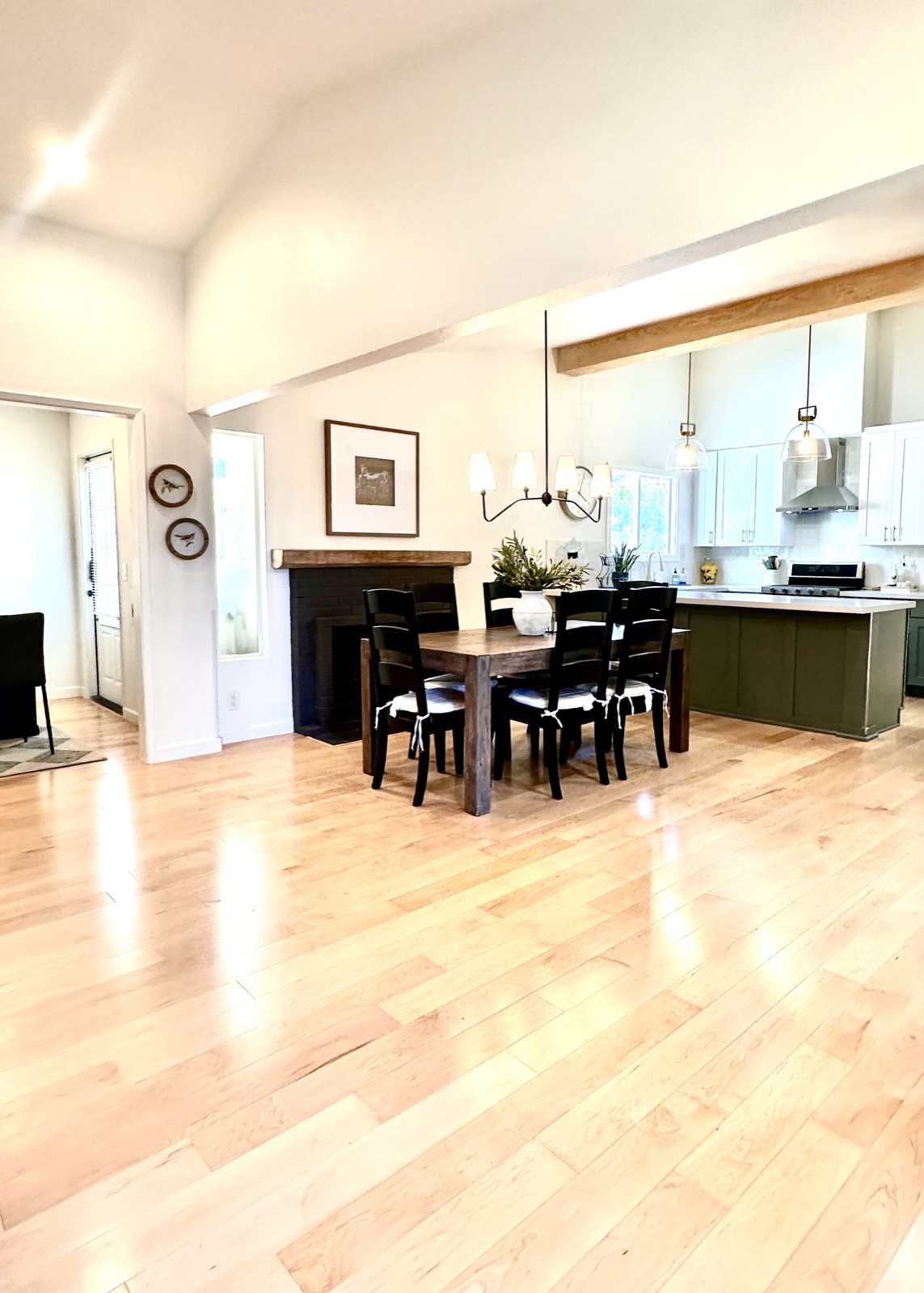 Open dining area with a fireplace mantel and view into the kitchen