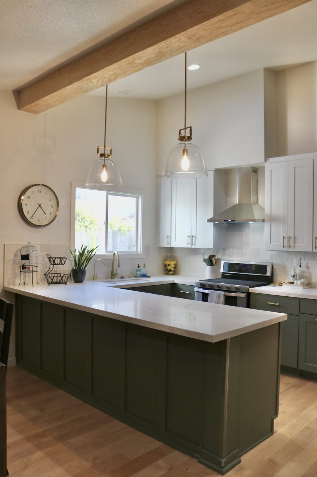 Kitchen with a green island, white cabinetry, and lit pendant lights