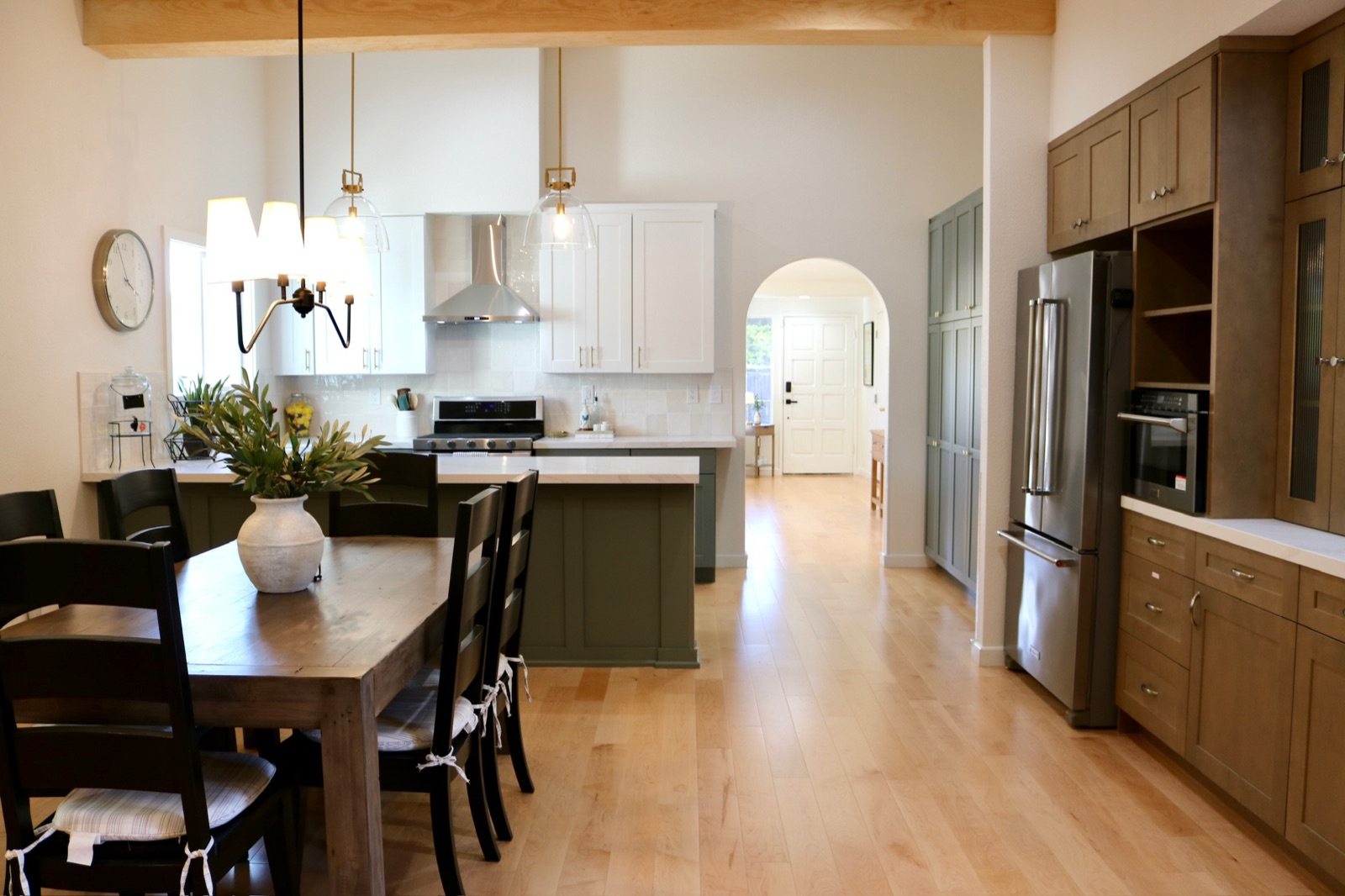 Open kitchen and dining area with an arched hallway and stainless appliances