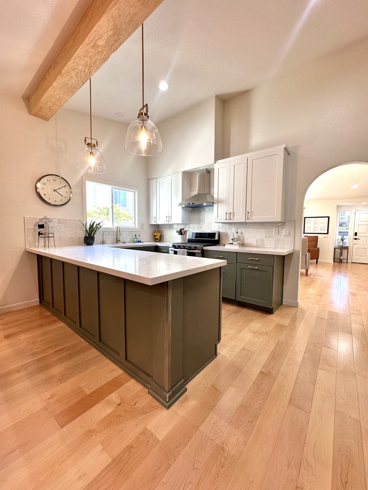 Kitchen peninsula with pendant lighting, white cabinets, and a wall clock