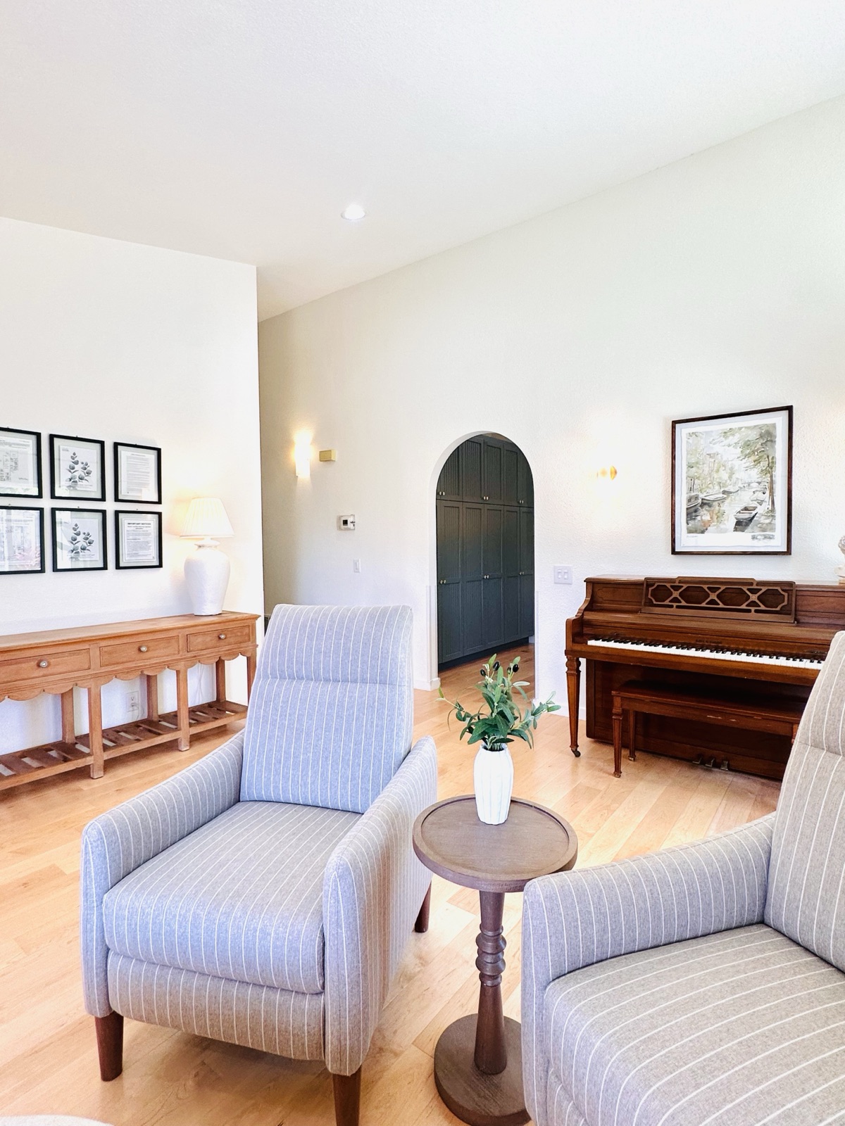 Living room with a gallery wall, console table lamp, and arched doorway