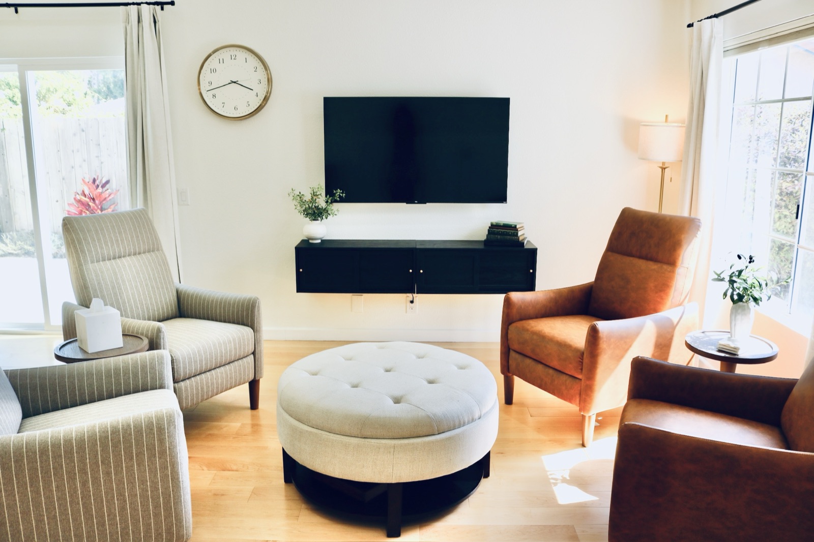 Living room with a lit floor lamp, television, and comfortable seating around an ottoman