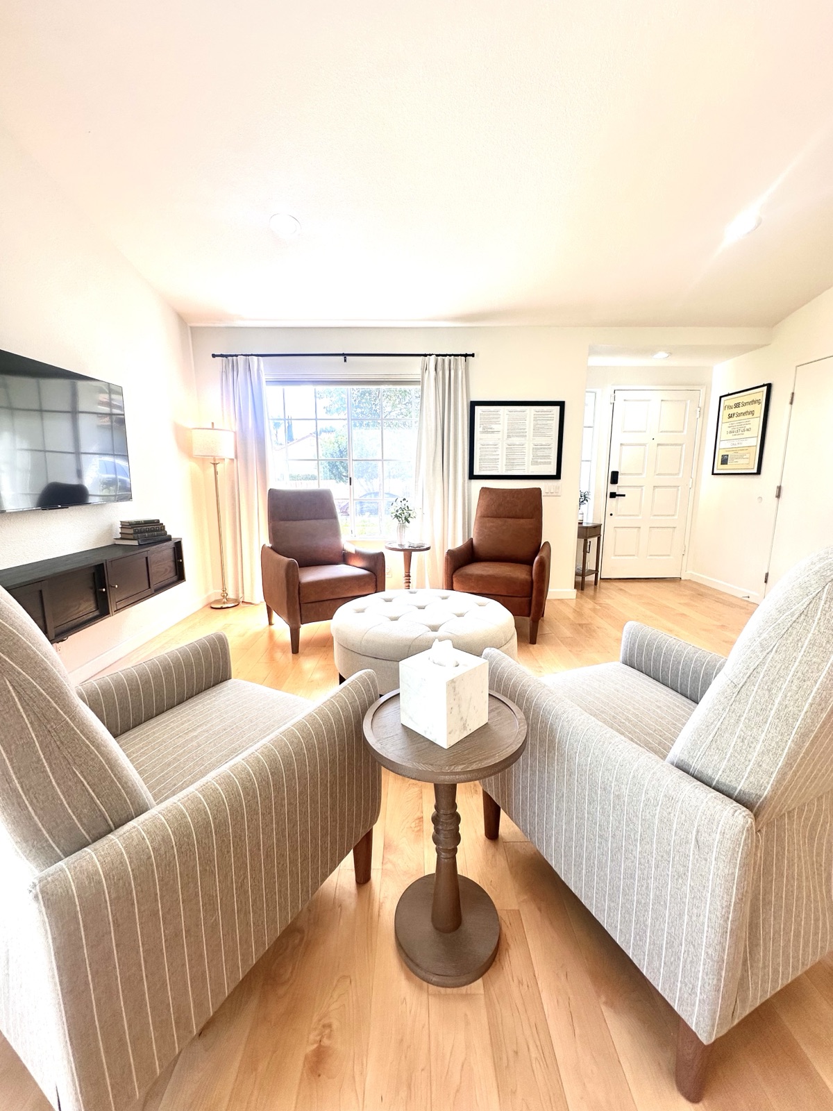 Living room looking toward the entry with striped armchairs and a floor lamp