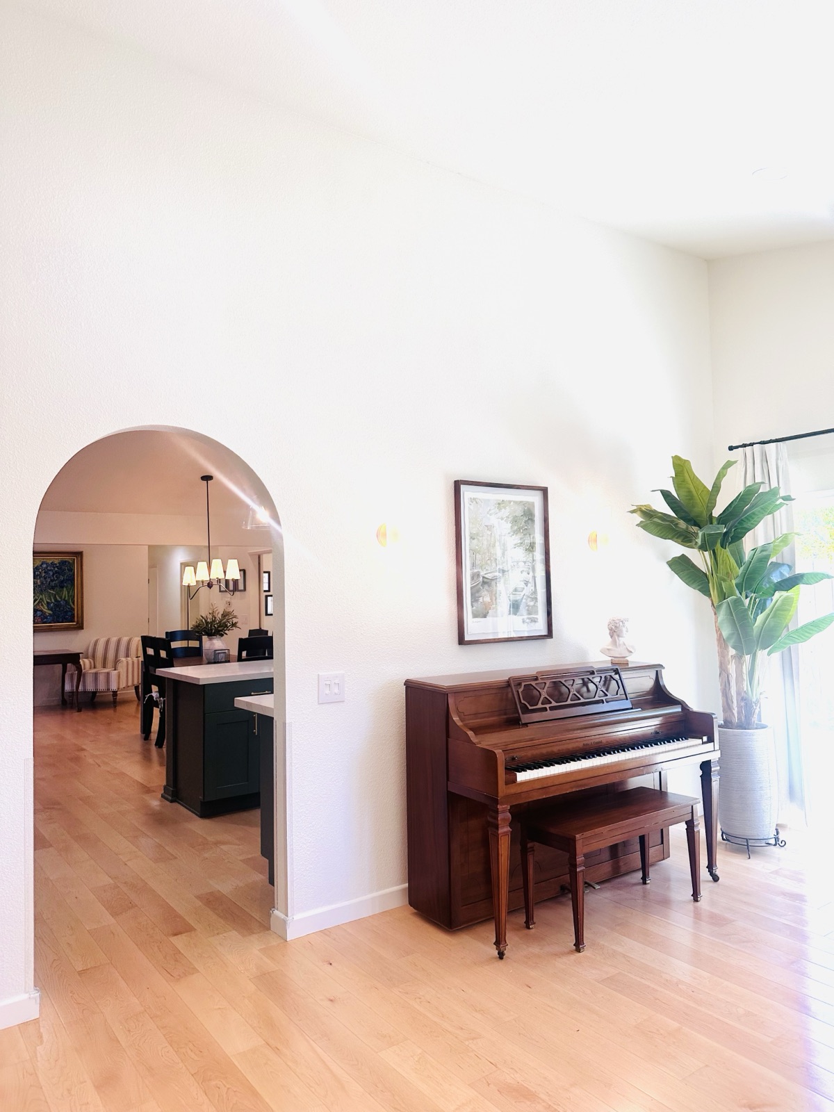 Piano corner viewed through an arched doorway from the entry