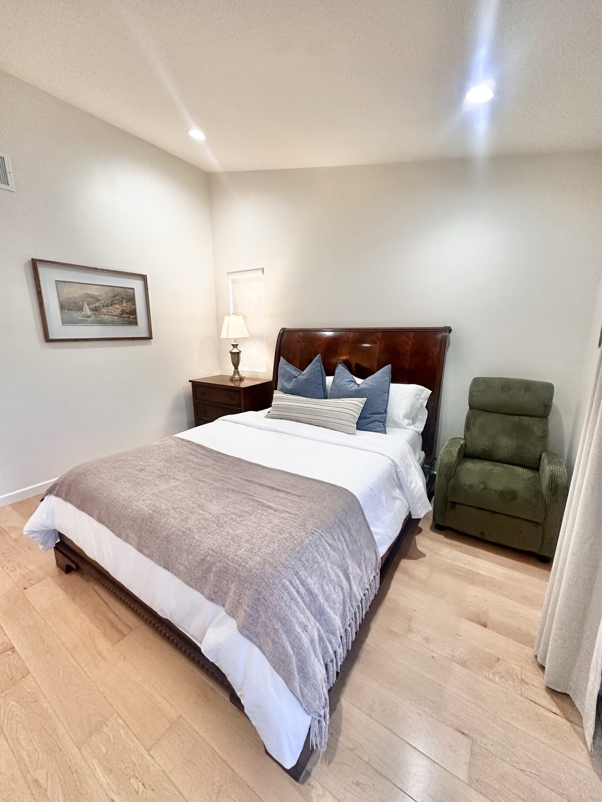 Master bedroom with a lit bedside lamp, framed art, and a lounge recliner
