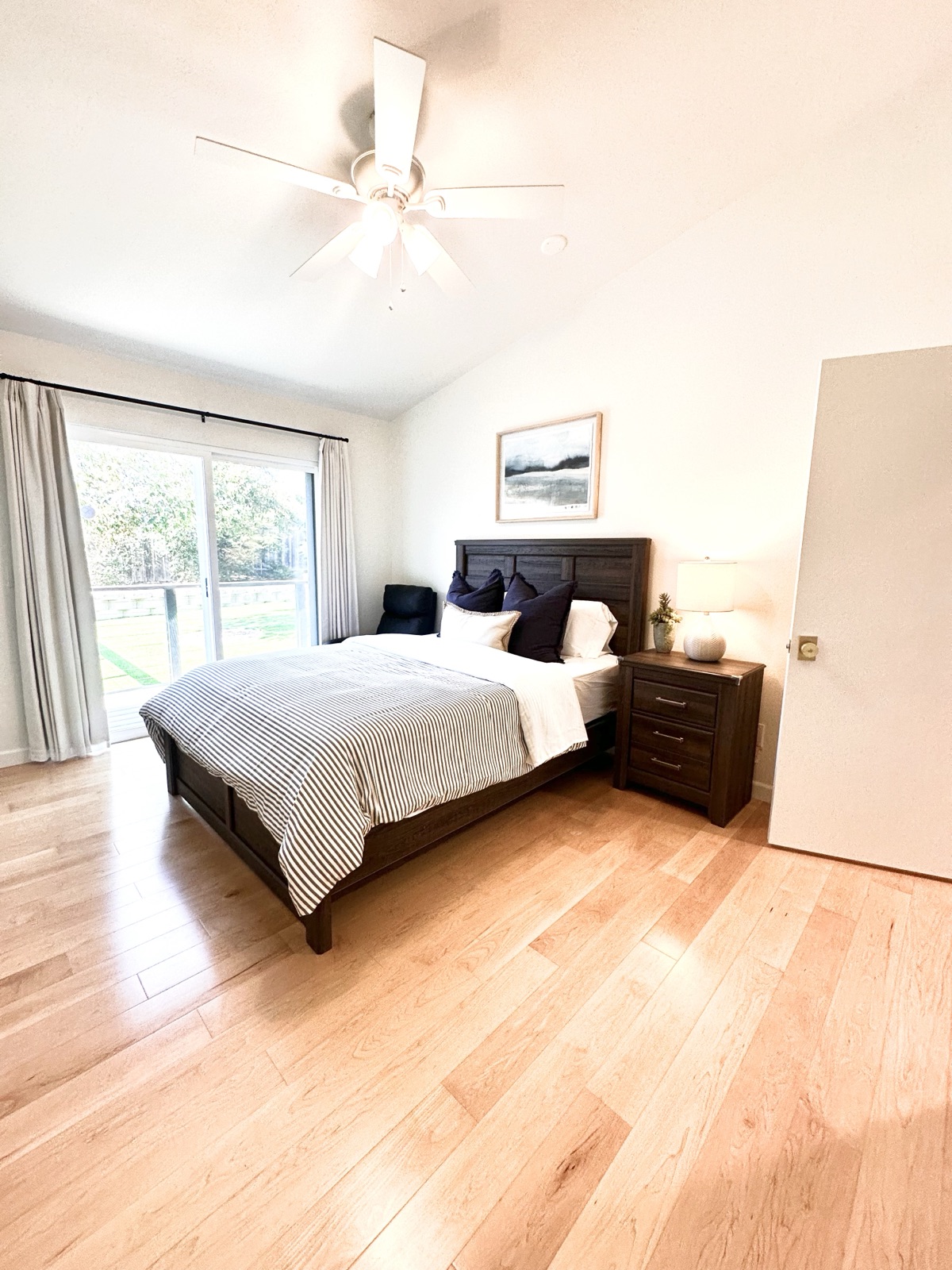 Private room with a dark wood bed, ceiling fan, and sliding door to the yard