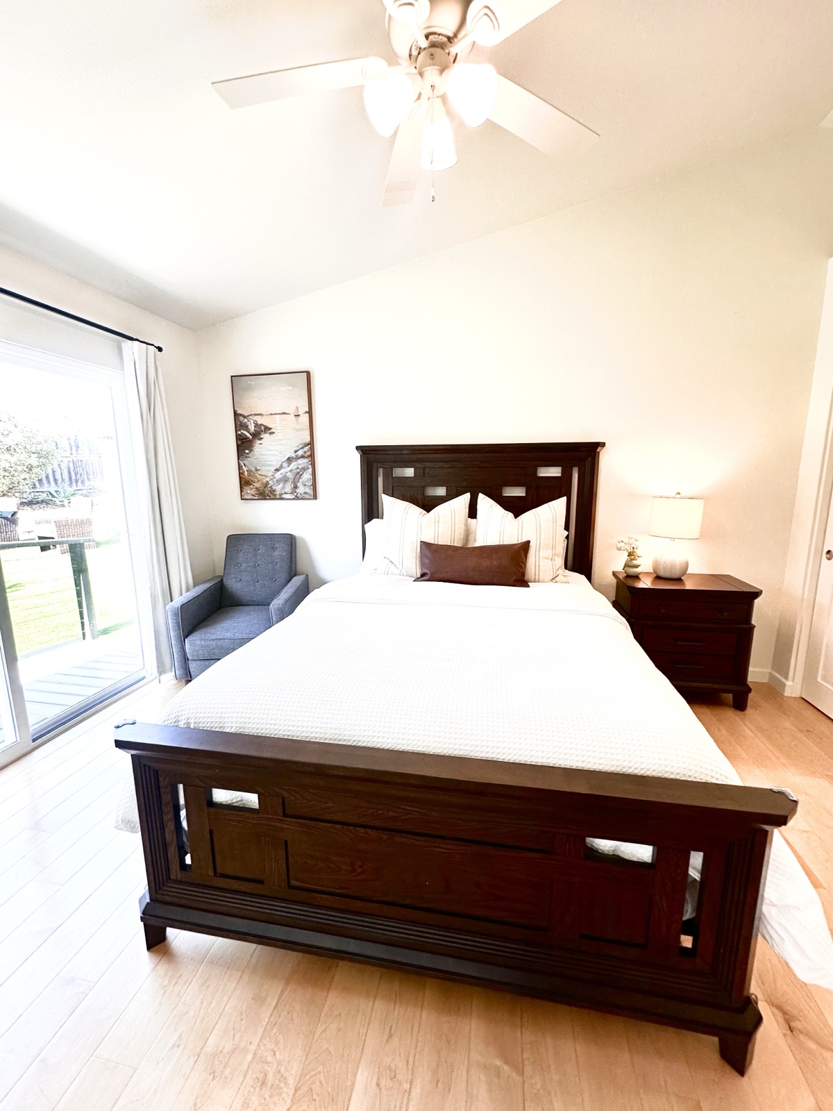 Private room with a reading chair, warm bedside lighting, and a ceiling fan